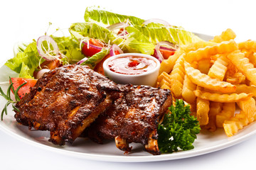 Grilled ribs, French fries and vegetables on white background 