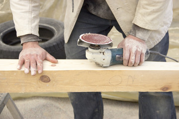 a man with a beard, a builder, working with wood, wood grinder g
