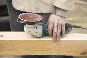 a man with a beard, a builder, working with wood, wood grinder g