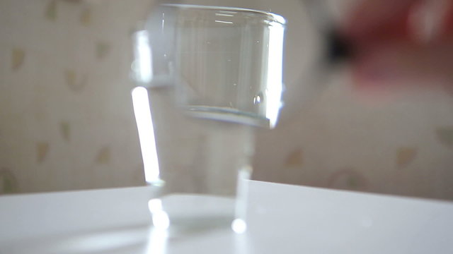 Glass of Water Being Inspected with  Magnifying Glass
