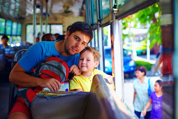 father and son traveling in public bus through asian city - obrazy, fototapety, plakaty