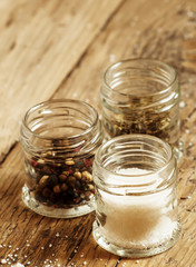 Spices: salt, pepper and herbs in small glass jar on a wooden ta