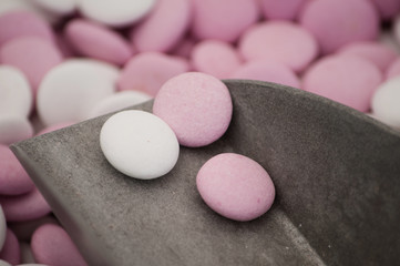 Two pink and one white candies on the scoop