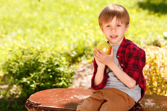 Boy sitting on bench and holding apple 