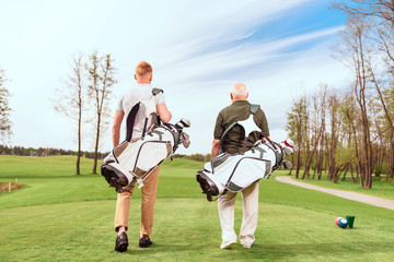 Back view of walking golf players on course