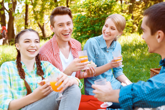 Young people eating and drinking during picnic 