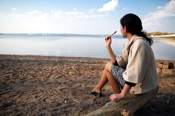 pretty girl sitting on lake coast and eating ice cream