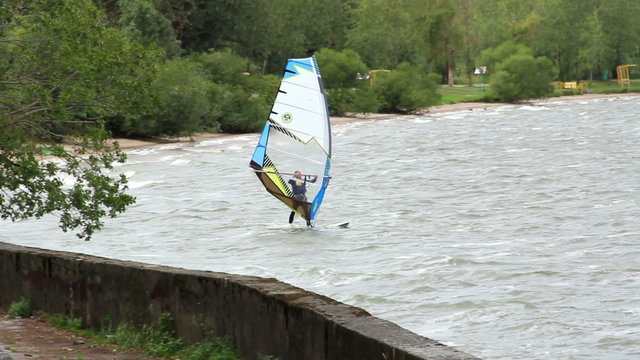 Surfing on the board with a sail in the lake 