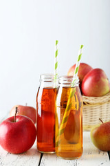 Bottles of apple juice with apples on white wooden background