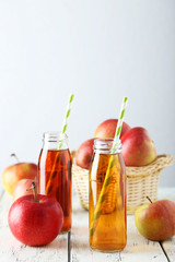 Naklejka na ściany i meble Bottles of apple juice with apples on white wooden background