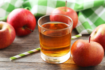 Glass of apple juice with apples on grey wooden background