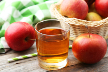Glass of apple juice with apples on grey wooden background