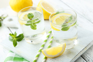 Fresh lemonade with lemon on white wooden background