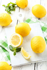 Lemons on cutting board on white wooden background