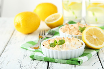 Lemon meringue pie in bowl on white wooden background