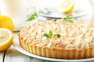 Lemon meringue pie on plate on white wooden background