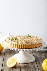 Lemon meringue pie on cake stand on grey wooden background
