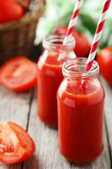 Fresh red tomatos in basket and juice in bottles 