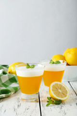 Tasty lemon jelly in glass on white wooden background
