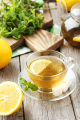 Cup of tea with mint and lemon on grey wooden background