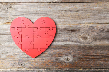Red puzzle heart on grey wooden background