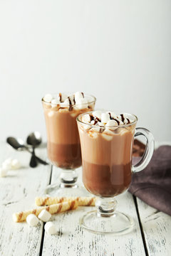 Glasses of hot chocolate with marshmallows on white wooden backg