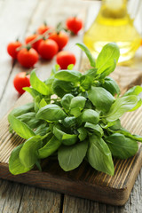 Basil leaves on cutting board on grey wooden background