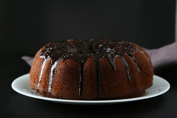Chocolate bundt cake on plate on black background