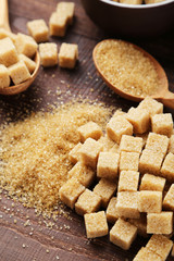 Brown sugar in spoon on brown wooden background