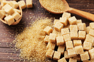 Brown sugar in spoon on brown wooden background