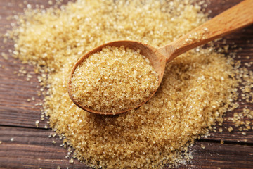 Brown sugar in spoon on brown wooden background