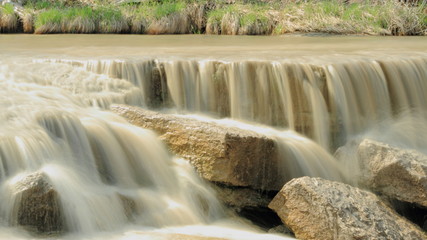 Small Waterfall Tumbling Over Stones Across A River
