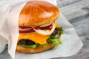 Homemade packed cheeseburger wrapped in paper - 83834549