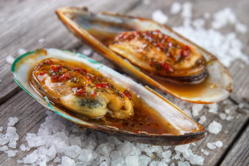 Cooked greenshell mussels on wooden board with sea salt