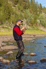 Fisherman catches a salmon in the north river.