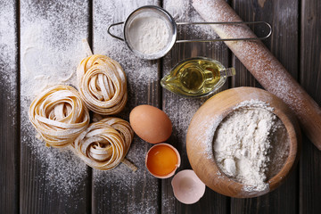 Raw homemade pasta and ingredients for pasta on wooden background