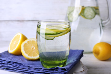 Fresh water with lemon and cucumber in glassware on wooden background