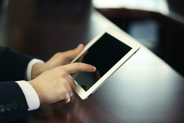 Businessman working with tablet at wooden table, closeup