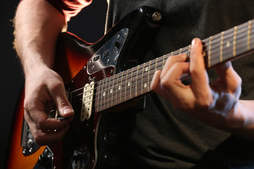 Fototapeta premium Young man playing on electric guitar close up