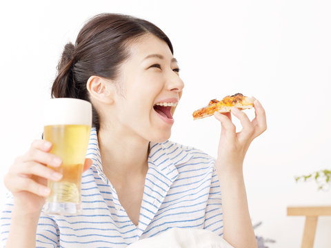 ビールとピザを持つ女性