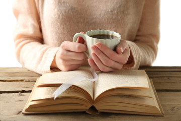 Woman holding cup of coffee and read the book, close up