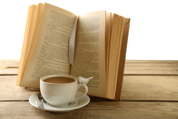 Still life with cup of coffee and book on wooden table, on white background