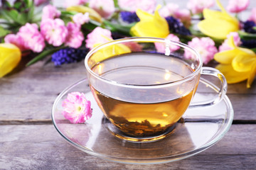 Cup of herbal tea with flowers on wooden background