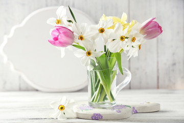 Spring bouquet in glass mug on color wooden background