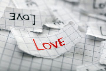 Word LOVE written on torn paper, closeup