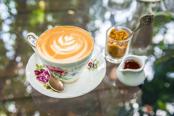 latte coffee with brown sugar and syrup jar on the glass table.