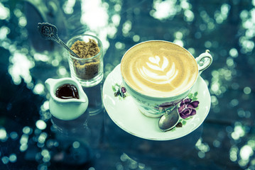 Obraz na płótnie Canvas latte coffee with brown sugar and syrup jar on the glass table.