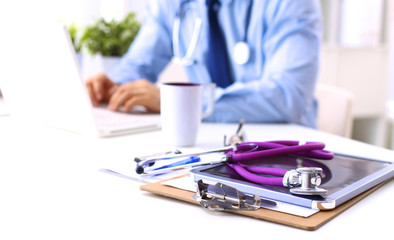 Male doctor using a laptop, sitting at his desk