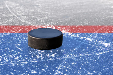 black hockey puck on ice rink - obrazy, fototapety, plakaty