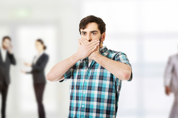 Young shocked man covering his mouth.